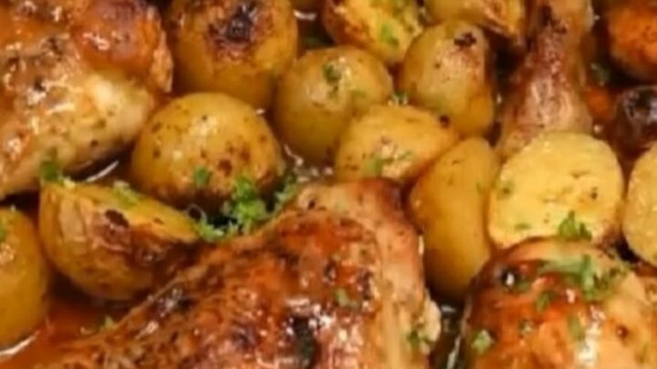 A stainless steel roasting pan filled with golden-brown honey garlic chicken thighs and roasted baby potatoes.