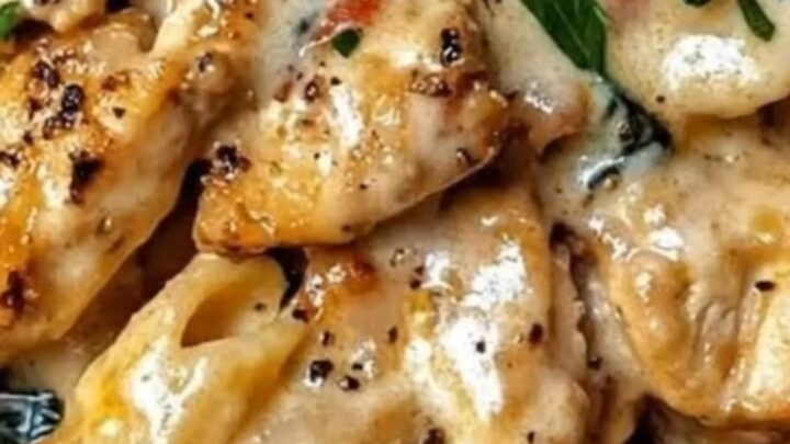 A close-up of creamy garlic chicken penne in a skillet with rising steam.