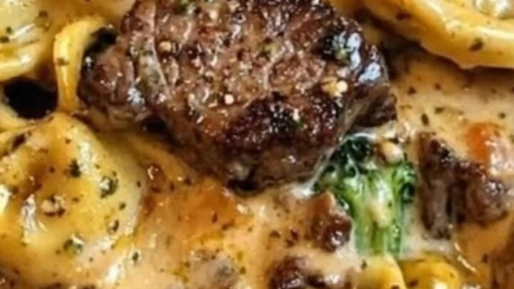 Skillet filled with creamy garlic parmesan tortellini, seared steak bites, and broccoli.