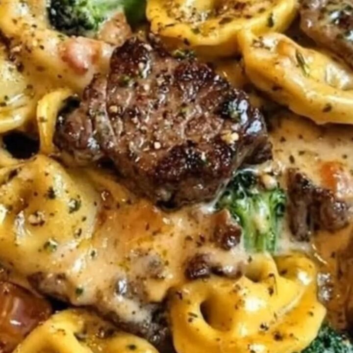Skillet filled with creamy garlic parmesan tortellini, seared steak bites, and broccoli.