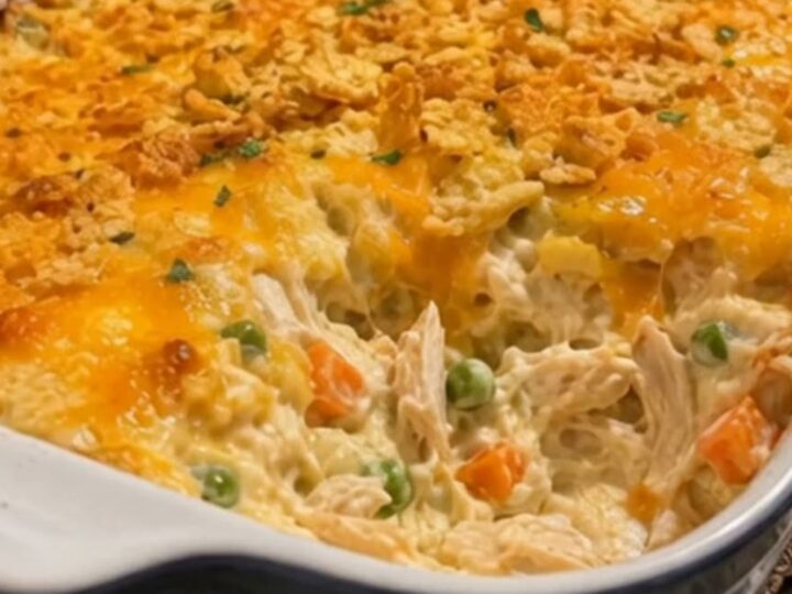 A close-up shot of a serving spoon scooping hot, steaming Chicken Gloria Casserole from a blue baking dish.