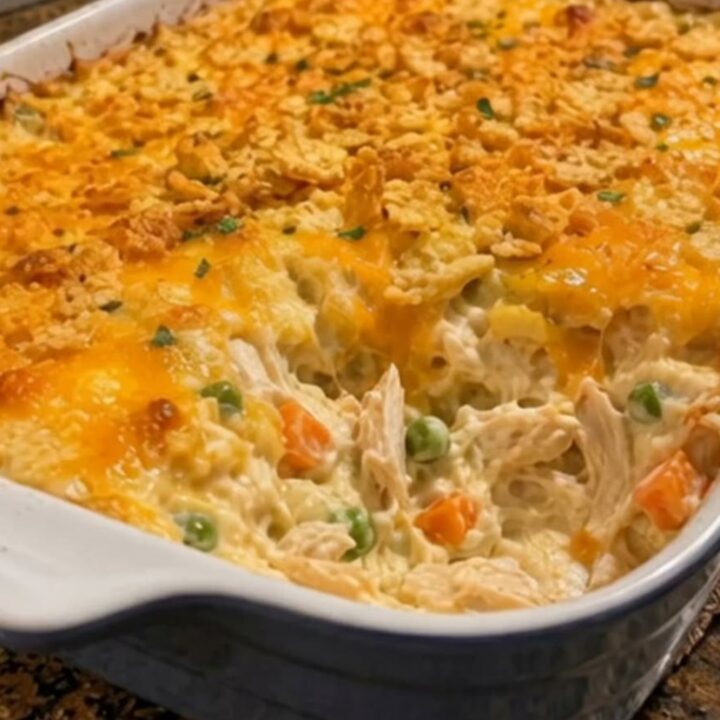 A close-up shot of a serving spoon scooping hot, steaming Chicken Gloria Casserole from a blue baking dish.