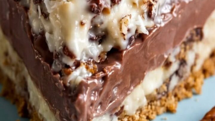 A close-up shot of a slice of sugar-free German chocolate pie on a soft blue plate, displaying distinct layers.
