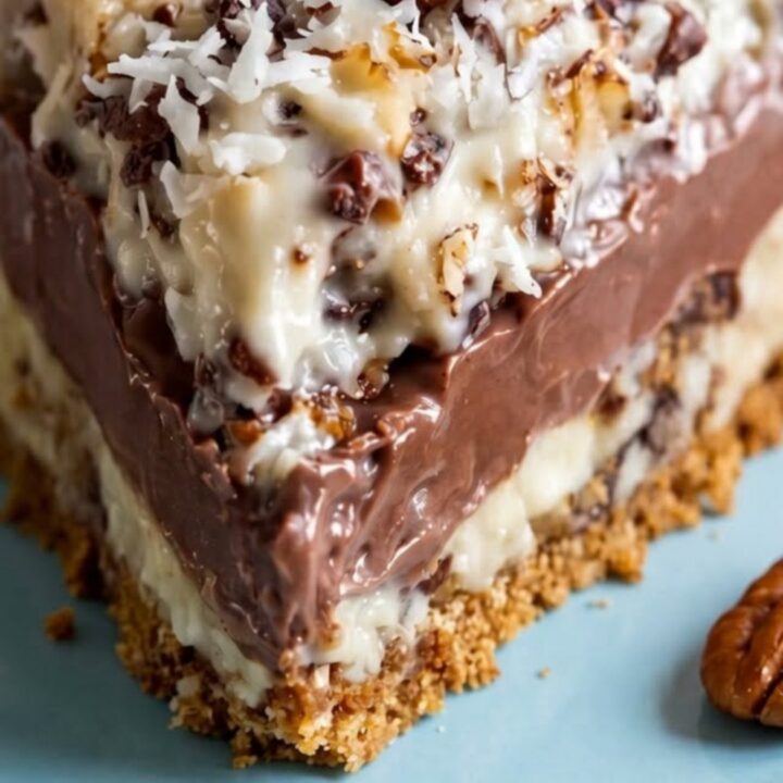 A close-up shot of a slice of sugar-free German chocolate pie on a soft blue plate, displaying distinct layers.