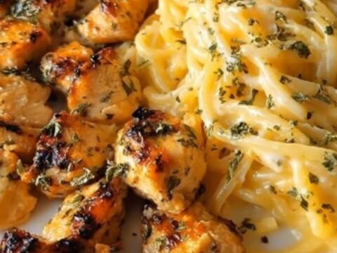 A close-up of creamy garlic butter chicken spaghetti in a skillet with tongs lifting the pasta.