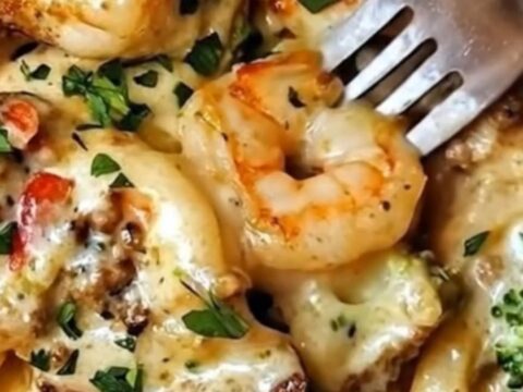 A close-up view of creamy shrimp alfredo linguine with bright green broccoli florets in a skillet.