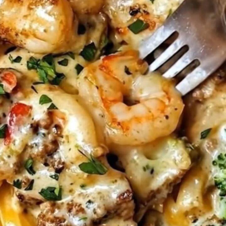 A close-up view of creamy shrimp alfredo linguine with bright green broccoli florets in a skillet.