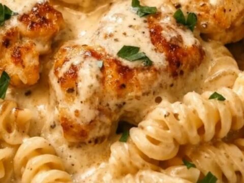 A close-up of a creamy garlic butter chicken and rotini pasta dish in a skillet.