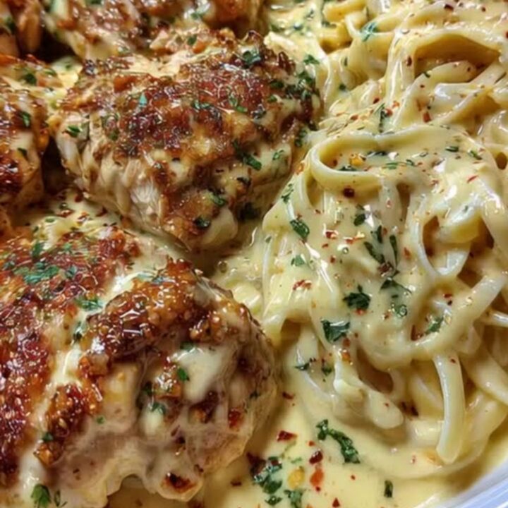 A plate of creamy Cajun Alfredo pasta alongside sliced golden-brown chicken cutlets garnished with herbs