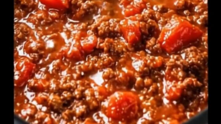 A steaming bowl of thick Italian meat sauce served in a bright home kitchen.