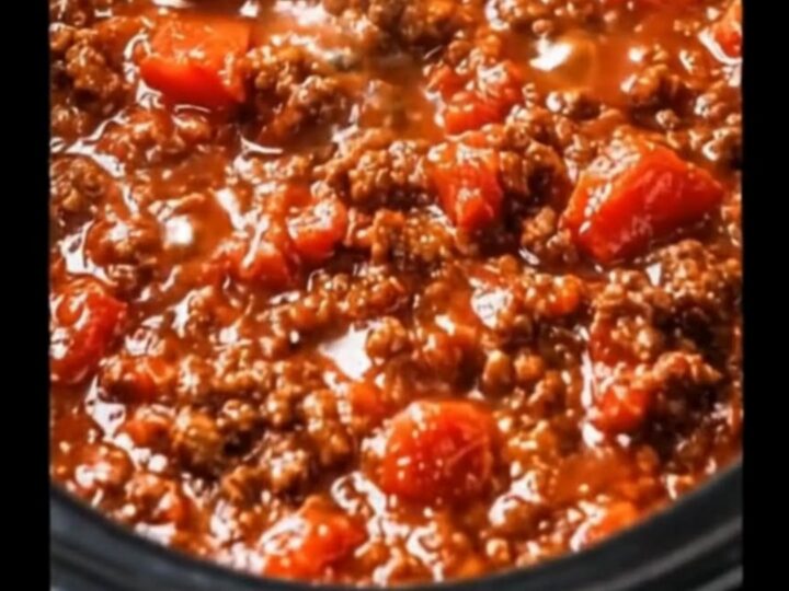 A steaming bowl of thick Italian meat sauce served in a bright home kitchen.