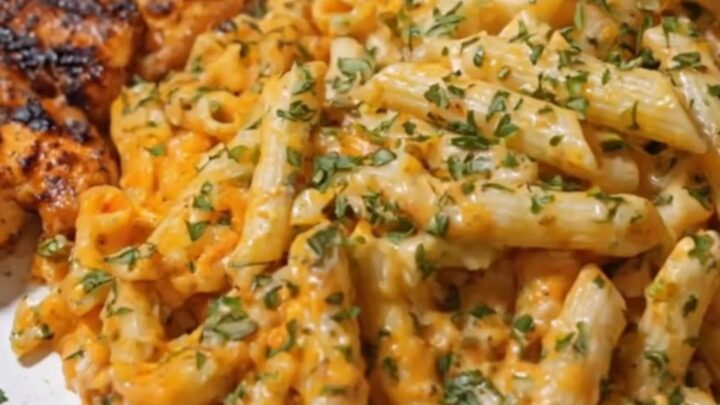 A close-up of garlic butter Cajun chicken penne in a skillet topped with fresh parsley.