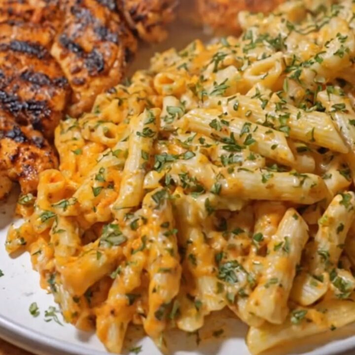 A close-up of garlic butter Cajun chicken penne in a skillet topped with fresh parsley.