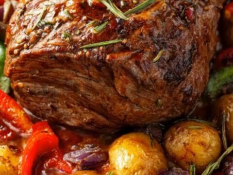 A juicy slice of herb-crusted roast beef being carved, surrounded by golden roasted potatoes and colorful bell peppers.