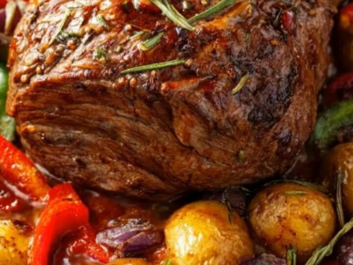 A juicy slice of herb-crusted roast beef being carved, surrounded by golden roasted potatoes and colorful bell peppers.