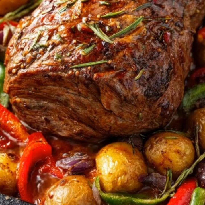 A juicy slice of herb-crusted roast beef being carved, surrounded by golden roasted potatoes and colorful bell peppers.