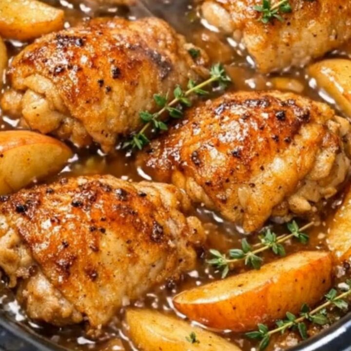 Slow cooker apple cider chicken with tender apple slices served on a white plate.