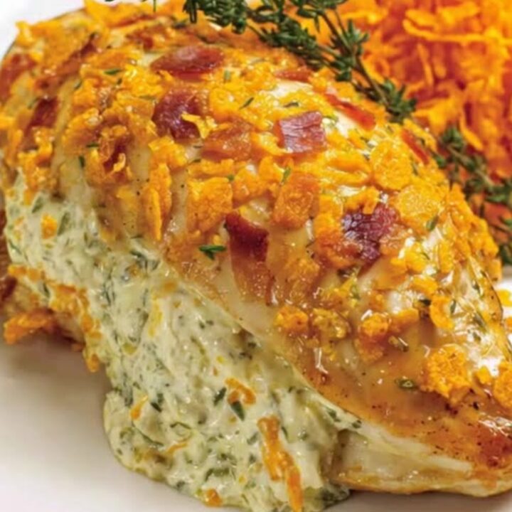 A close-up of a golden, crispy Doritos-crusted chicken breast overflowing with warm herb cream cheese