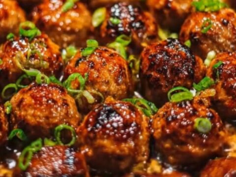 Sticky honey garlic meatballs in a cast-iron skillet garnished with fresh green onions.