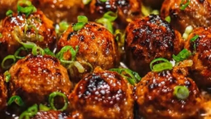 Sticky honey garlic meatballs in a cast-iron skillet garnished with fresh green onions.