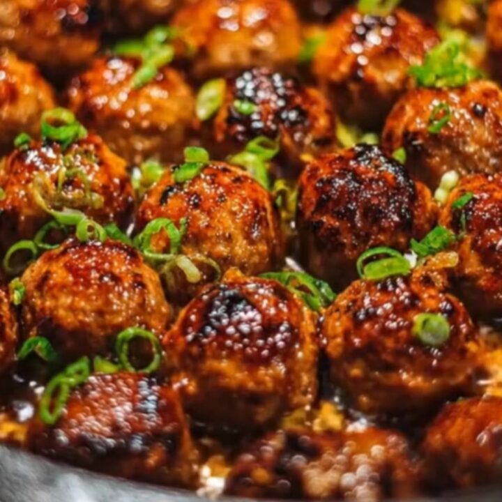 Sticky honey garlic meatballs in a cast-iron skillet garnished with fresh green onions.