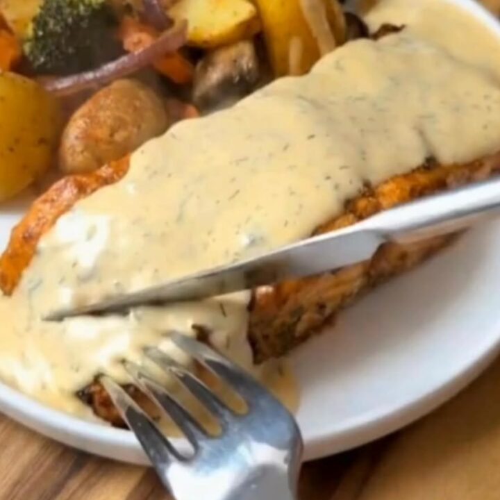 A beautifully plated herb-crusted salmon fillet with roasted baby potatoes and broccoli.