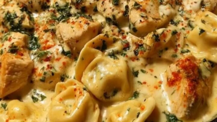 A close-up of a creamy chicken tortellini skillet in a black cast-iron pan with fresh herbs.
