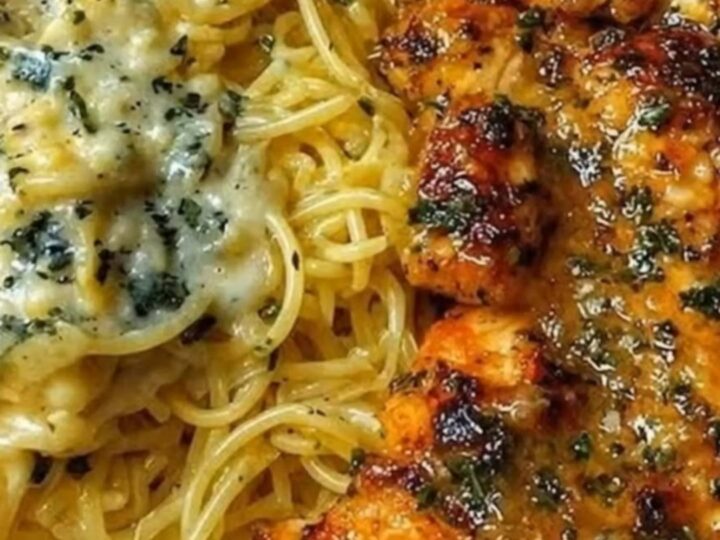 A close-up of creamy parmesan spaghetti topped with golden-brown seared chicken pieces.