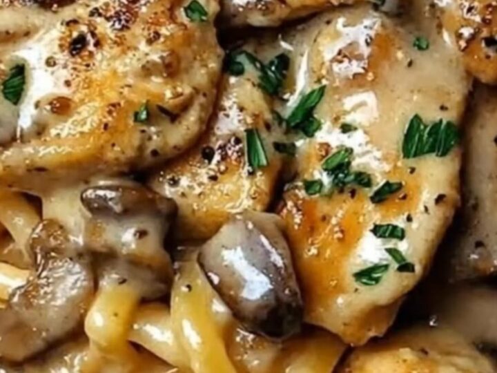 A close-up of creamy Cajun chicken linguine with mushrooms in a skillet with tongs.