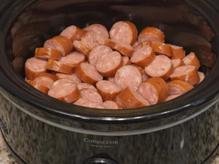 Close up of glazed smoked sausage and pineapple chunks in a black slow cooker