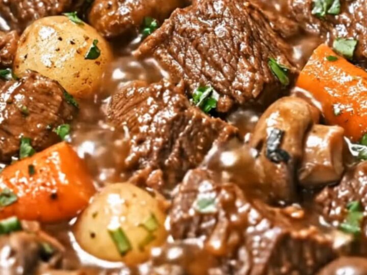 A steaming, rich bowl of beef stew featuring tender chunks of beef, carrots, and potatoes.