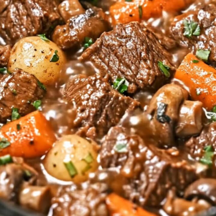 A steaming, rich bowl of beef stew featuring tender chunks of beef, carrots, and potatoes.