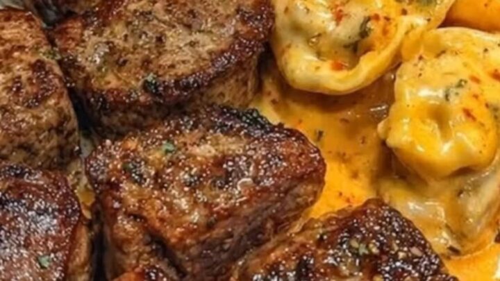 A close-up of garlic butter steak bites and cheesy tortellini on a white plate.