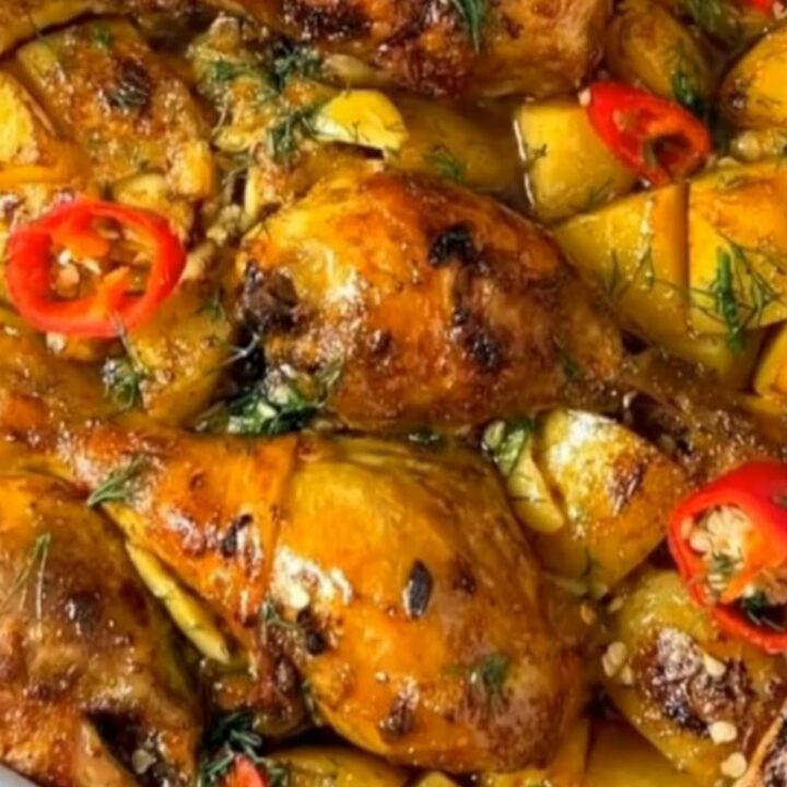 Golden-brown roasted chicken drumsticks and potatoes in a roasting dish garnished with fresh dill.