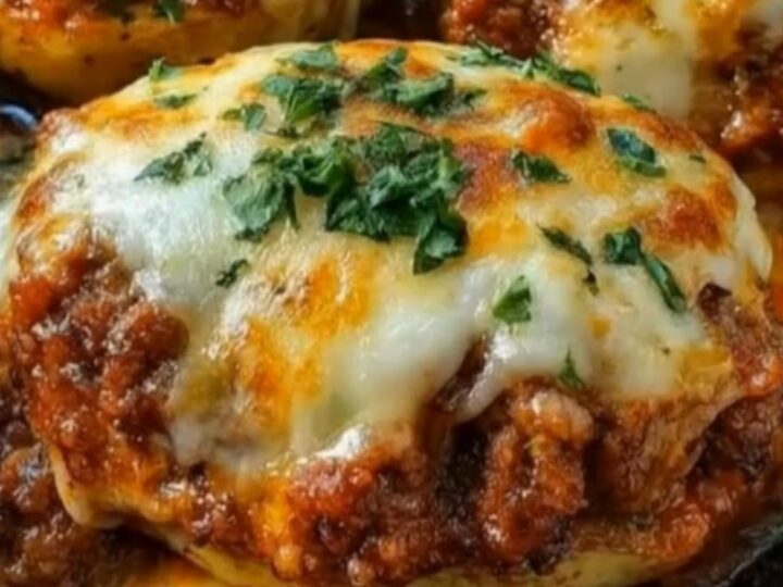 A close-up of a baked potato stuffed with seasoned ground beef and melted mozzarella cheese in a cast-iron skillet.