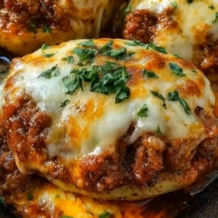 A close-up of a baked potato stuffed with seasoned ground beef and melted mozzarella cheese in a cast-iron skillet.