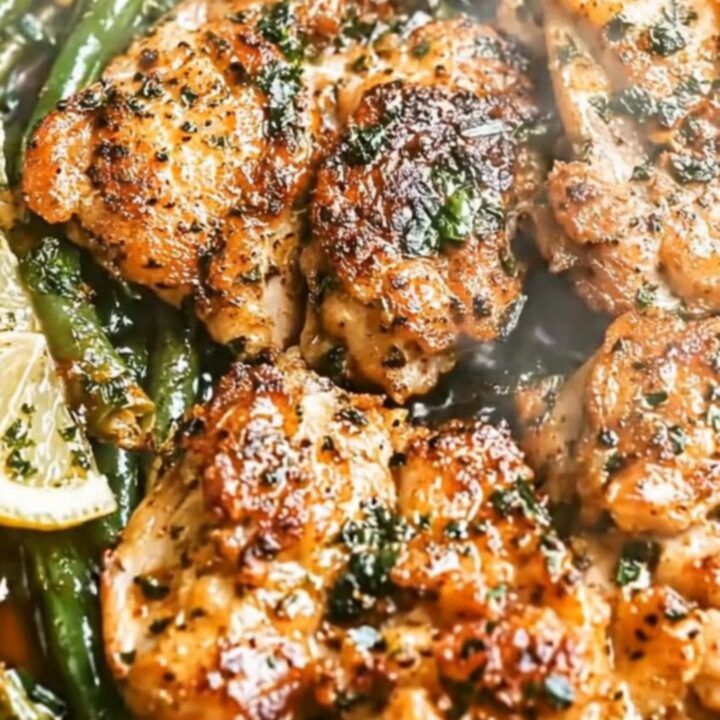 A golden-seared chicken thigh and green beans served on a white plate.