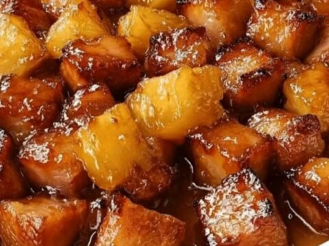 A white baking dish filled with caramelized, glossy brown sugar pineapple ham bites.