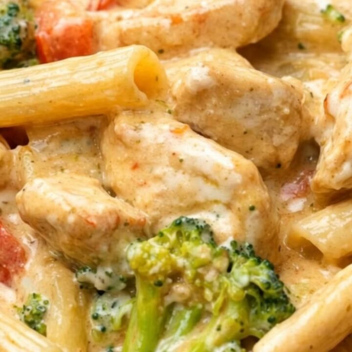 A steaming, creamy chicken penne pasta dish in a skillet with broccoli and peppers.