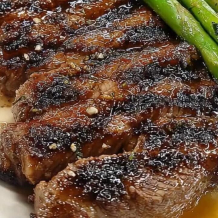A platter featuring a perfectly seared medium-rare steak sliced into strips next to charred asparagus.