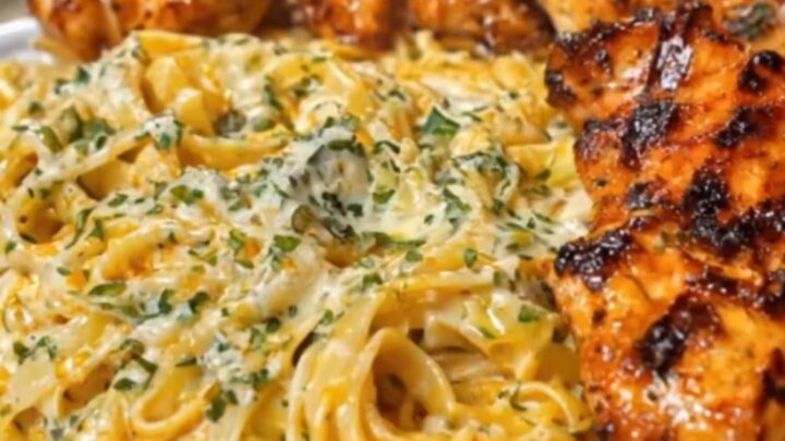 A white platter filled with creamy Cajun chicken linguine, topped with golden-brown chicken strips.