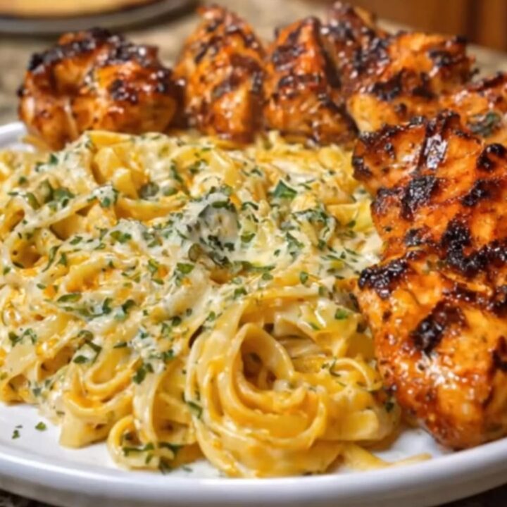 A white platter filled with creamy Cajun chicken linguine, topped with golden-brown chicken strips.