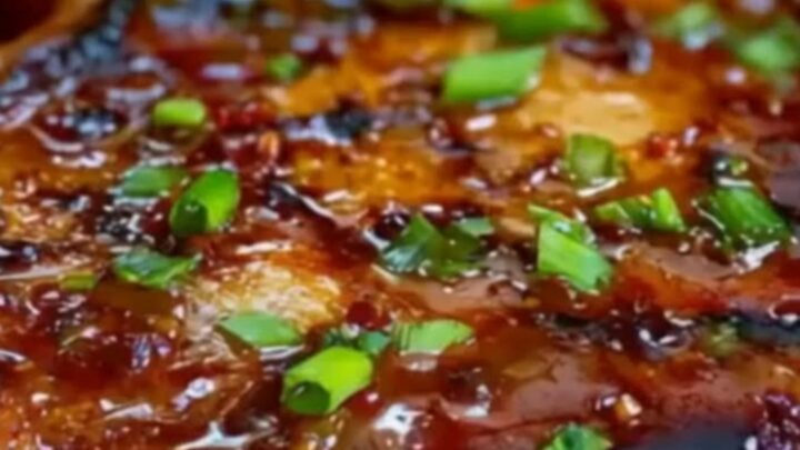 A close-up of a perfectly seared pork chop topped with caramelized peach slices and a glossy glaze.
