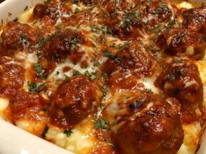 Cheesy meatball and mashed potato bake in a white square ceramic baking dish with melted mozzarella.
