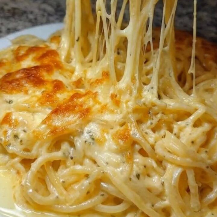 A steaming plate of creamy parmesan spaghetti with a thick, glossy sauce.