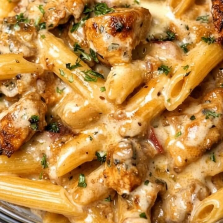 A steaming bowl of creamy garlic butter chicken penne garnished with fresh chopped parsley.