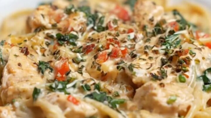 A steaming bowl of creamy garlic parmesan chicken linguine with fresh spinach and herbs.