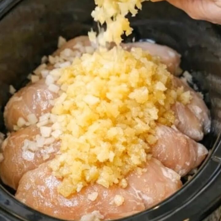 A close-up of tender chicken breasts covered in a glossy pineapple sauce on a white plate.