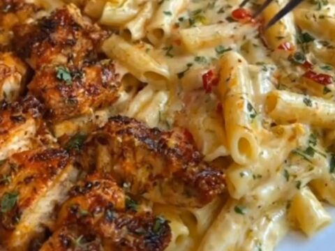 A steaming dish of creamy Cajun chicken penne in a baking dish with melted cheese.