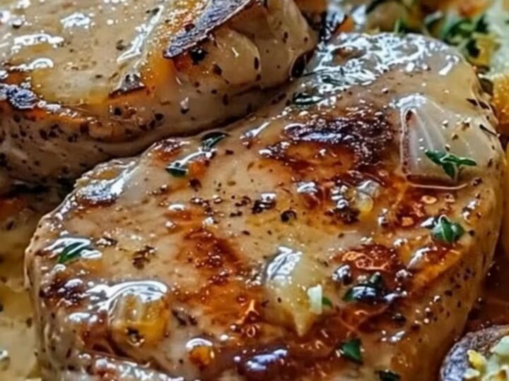 Golden-seared pork chop sitting in a cast-iron skillet with a creamy garlic sauce and roasted baby potatoes.